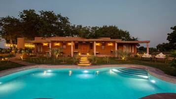 Una casa con piscina, porche cubierto e iluminación exterior.