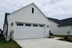 A single-story house with a white exterior, a garage with a white door, and a small front yard with two potted plants. - "Sweet Home Mississippi" by OVR (Oxxford)