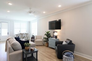 A living room with a sofa, armchair, TV, and a dining area with chairs and a table. - "Sweet Home Mississippi" by OVR (Oxxford)