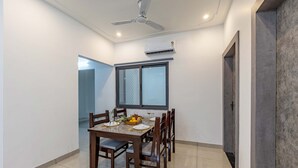 A dining area with a table set for six, a ceiling fan, and an air conditioning unit on the wall.