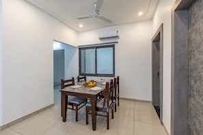 A dining area with a table set for six, a ceiling fan, and an air conditioning unit on the wall.