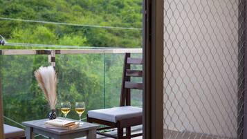 A balcony with a table, two glasses of white wine, a book titled 'The Laws of the Spirit World,' and a decorative feather.