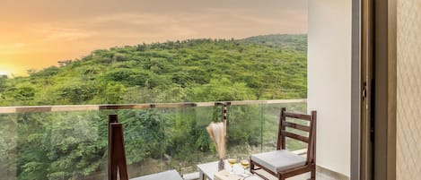 Ein Balkon mit zwei Holzstühlen und einem kleinen Tisch, mit Blick auf eine üppige grüne Landschaft.