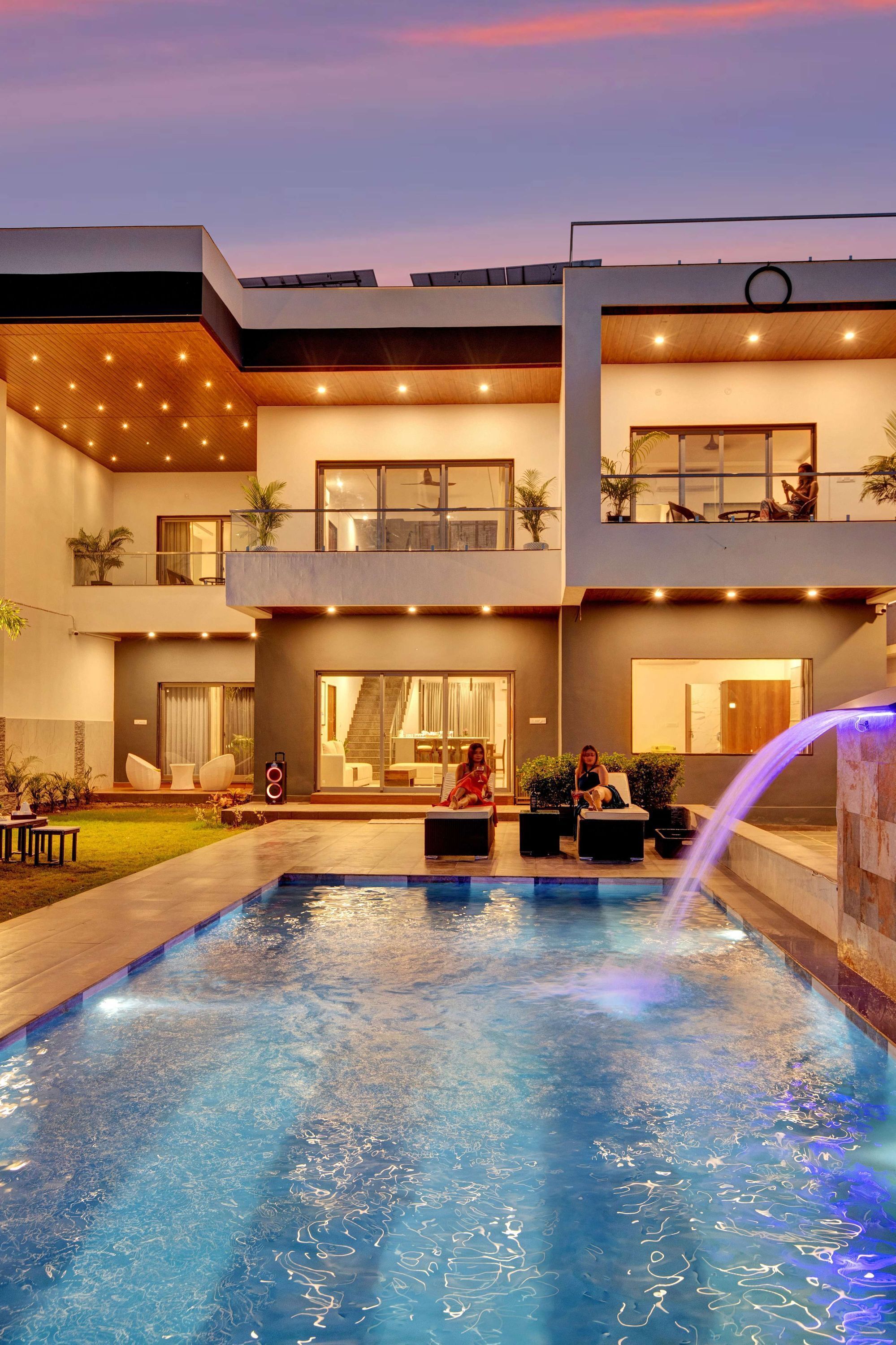 A modern multi-story building with a swimming pool and outdoor seating areas.