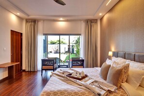 A hotel room with a large bed, a small table with drinks, a view of the outdoors, and a wooden floor. - The Horizon Villa by Viraalay - Premium 5bhk Villa (Udaipur)
