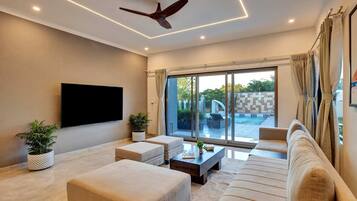 A modern living room with a flat-screen TV, a ceiling fan, and a large sliding glass door leading to an outdoor area.