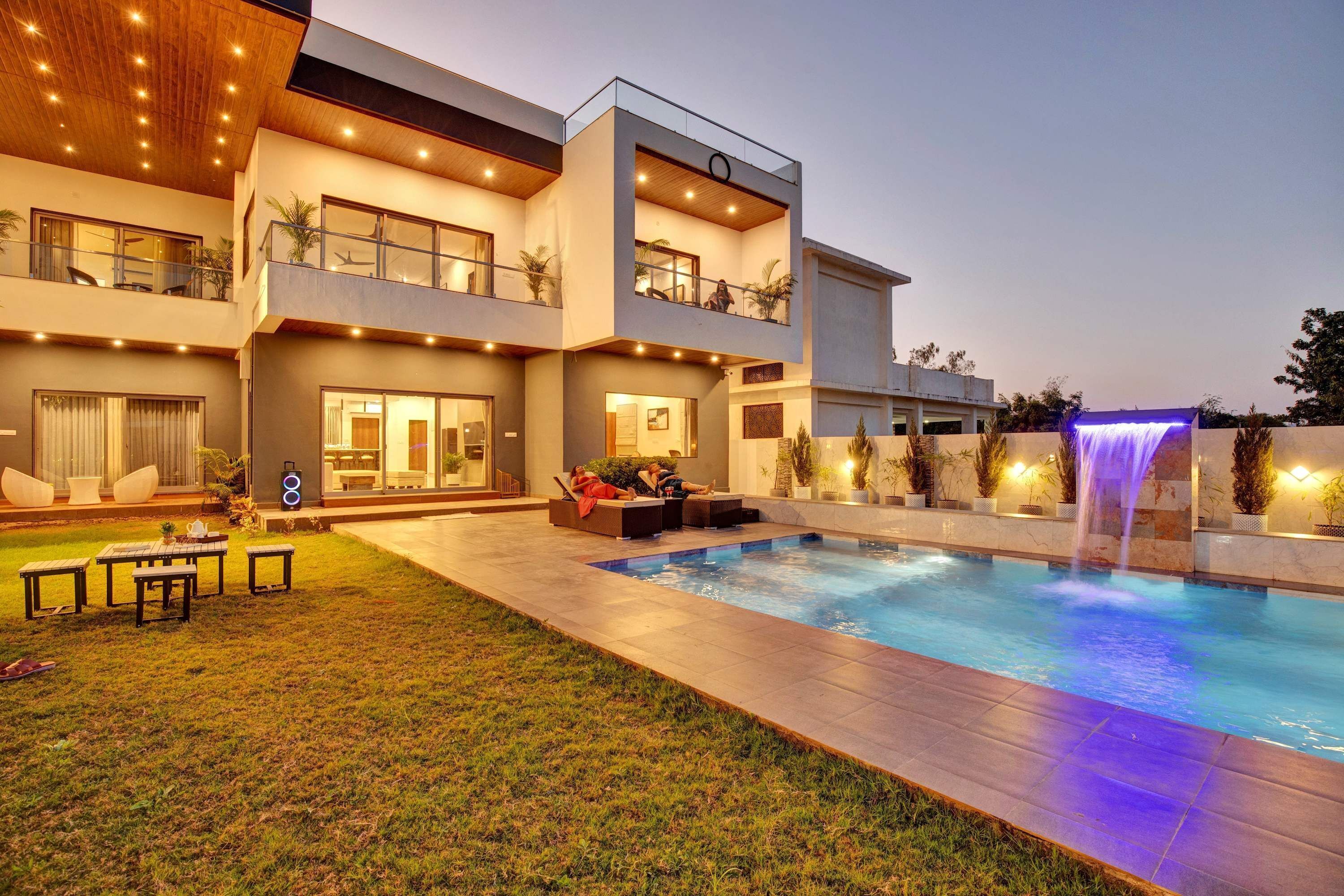 A modern two-story house with a swimming pool and a waterfall feature.