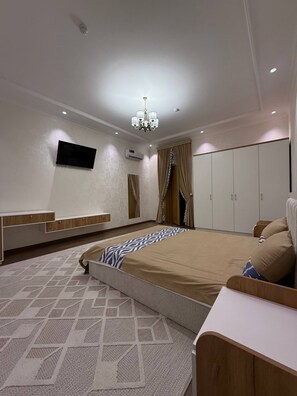 Un dormitorio moderno con una cama grande, televisión, armario y candelabro.
