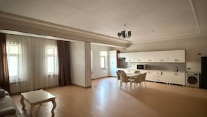 Amplia sala de estar con una mesa y sillas de comedor, un sofá y una cocina con armarios y electrodomésticos.