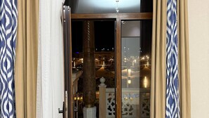 A sliding glass door leading to an outdoor area with a view of a cityscape at night.