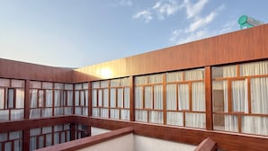 Un edificio moderno con techo plano, ventanas grandes con cortinas y cielo despejado.