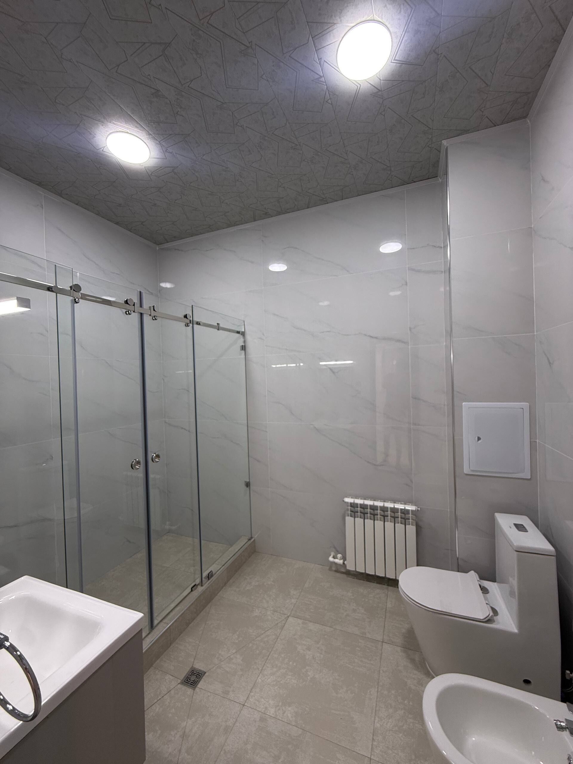 Casa de banho moderna com chuveiro envidraçado, lavatório branco e bidé.
