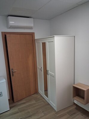 A room with a wooden door, a white wardrobe with two doors, and a small wooden shelf. - House Amara y Pablo (Madrid)