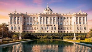 A large, classical building with a symmetrical facade, a central dome, and a reflecting pool in front. - House Amara y Pablo (Madrid)