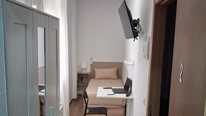 A compact room with a bed, a desk with a laptop, a chair, and a wardrobe. - House Amara y Pablo (Madrid)