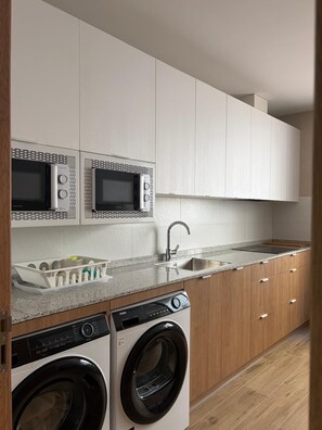 Una cocina compacta con electrodomésticos integrados, lavadora y lavaplatos.