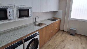 A modern kitchen with built-in appliances, a sink, and a window. - House Amara y Pablo (Madrid)