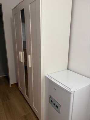 A room with a white wardrobe, a white cabinet, and a wooden floor.