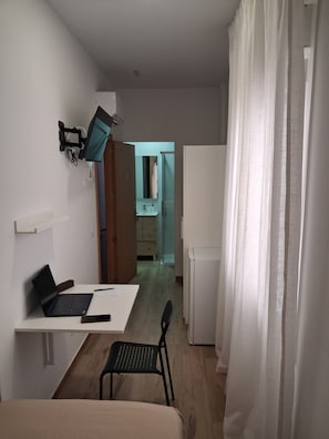 A room with a desk, chair, laptop, and a bed. There is a mirror on the wall and a door leading to another room. - House Amara y Pablo (Madrid)