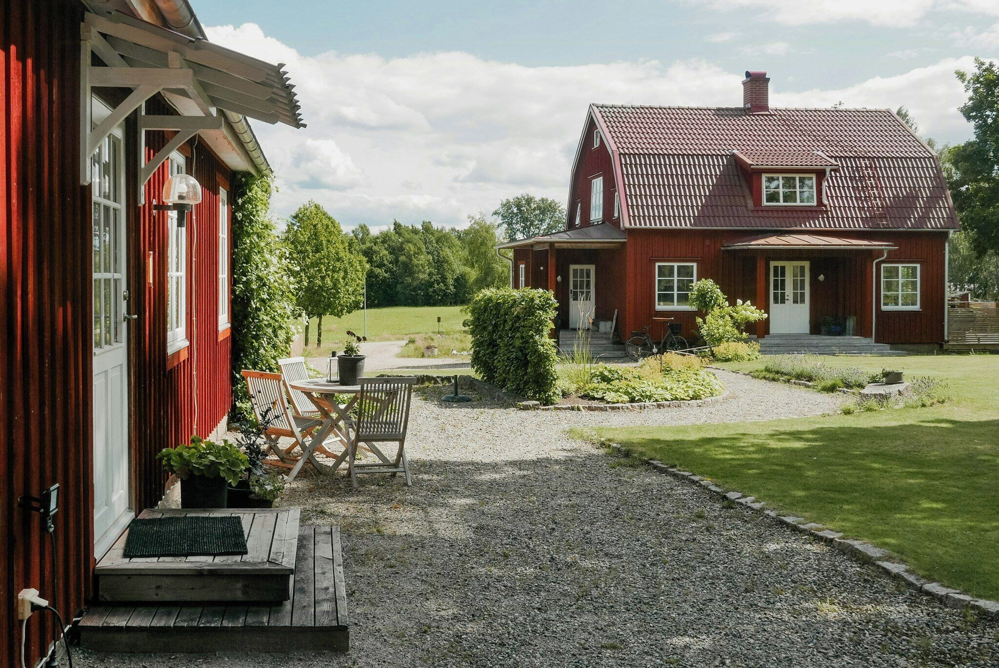 Une maison en bois rouge avec une allée en gravier et une pelouse.