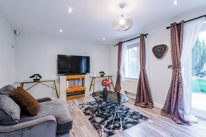 Un salon moderne avec un canapé, une table basse en verre, un téléviseur à écran plat et un tapis à motifs.