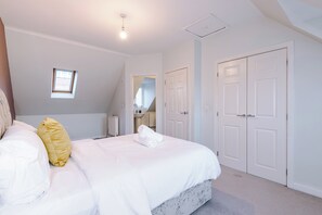 Une chambre à coucher avec un lit, une fenêtre, un radiateur et un ensemble de portes blanches.