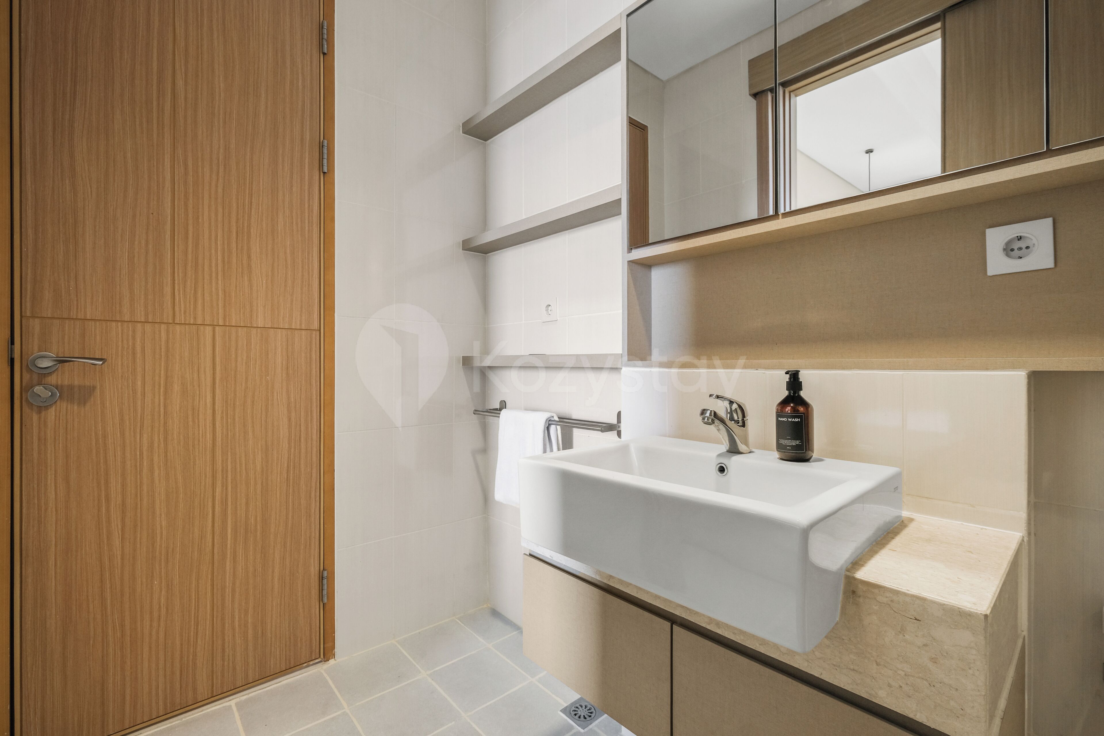 A modern bathroom with a wooden door, a white sink, and a mirror above it.