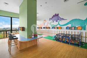 A children's play area with a dinosaur mural, a playhouse, and a ball pit. - Brayen by Kozystay - Tebet (South Jakarta)