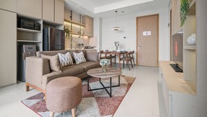 A modern kitchen with built-in appliances, a dining area with a table and chairs, and a living room with a sofa and coffee table. - Brayen by Kozystay - Tebet (South Jakarta)