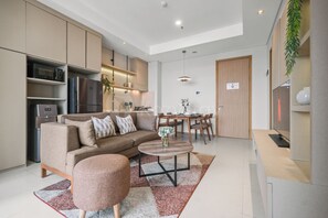 A modern kitchen with built-in appliances, a dining area with a table and chairs, and a living room with a sofa and coffee table. - Brayen by Kozystay - Tebet (South Jakarta)