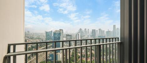 A balcony with a view of a cityscape, including buildings and roads.