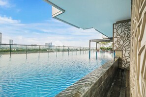A rooftop infinity pool with a city view, a covered seating area, and a decorative wall. - Brayen by Kozystay - Tebet (South Jakarta)