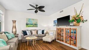 Ein Wohnzimmer mit Sofa, Sessel, Couchtisch und Fernseher auf einem Schrank.