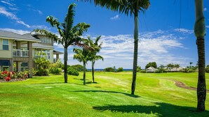 Ein gepflegter Golfplatz mit Clubhaus, Palmen und blauem Himmel.