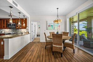 A modern kitchen with a central island, wooden flooring, and pendant lighting. - Pili Mai 6F by Alekona Kauai - 2BR Condo access to fitness (Koloa)