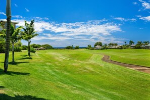 A golf course with a clear sky, palm trees, and a well-maintained lawn. - Pili Mai 6F by Alekona Kauai - 2BR Condo access to fitness (Koloa)