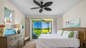 Ein Schlafzimmer mit einem Bett, einem Schminktisch, einer Lampe und einem Deckenventilator.