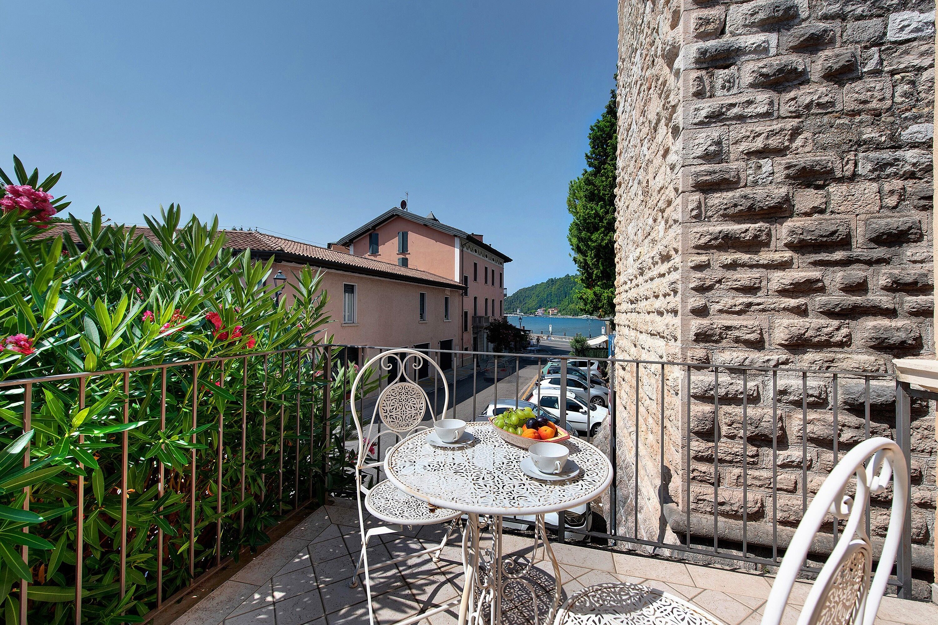 A balcony with a table, chairs, and a bowl of fruit.