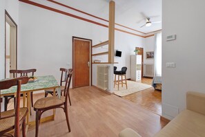 A room with a dining table, chairs, a sofa, a ceiling fan, and a radiator. - Casa Maderno: steps from the Lake (Toscolano Maderno)