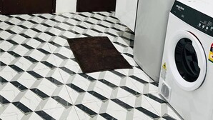 Un lavadero pequeño con lavadora, secadora y piso de baldosas.