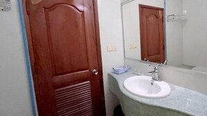 A bathroom with a wooden door, a white sink, a mirror, and a shower area. - Mongkol Angkor Residence & Spa (Siem Reap)