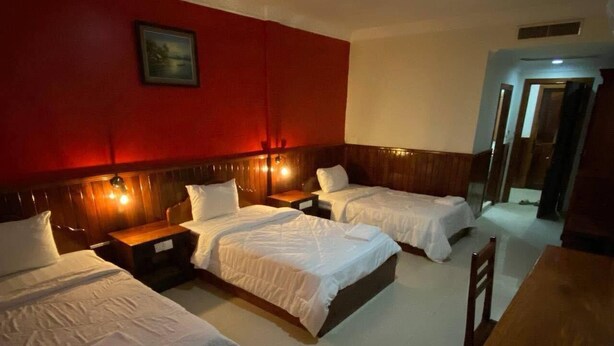 A hotel room with three beds, a wooden headboard, a small table, and a chair. - Mongkol Angkor Residence & Spa (Siem Reap)