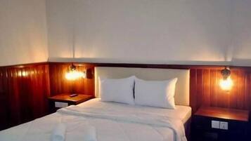 A hotel room with a bed, bedside tables, and an air conditioning unit.