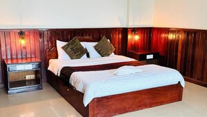 A wooden-framed bed with white linens and two pillows, a nightstand with a lamp, and a wall-mounted light fixture. - Mongkol Angkor Residence & Spa (Siem Reap)