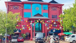 A red building with a blue facade, ATM/CASH in sign, and colorful flags. - Mongkol Angkor Residence & Spa (Siem Reap)