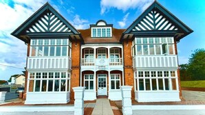 A two-story building with a symmetrical facade, a central entrance, and a balcony on the upper floor. - The Bay Apart-Hotel (Southwold)