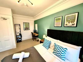 Habitación de hotel con cama, escritorio, silla y obras de arte en las paredes.