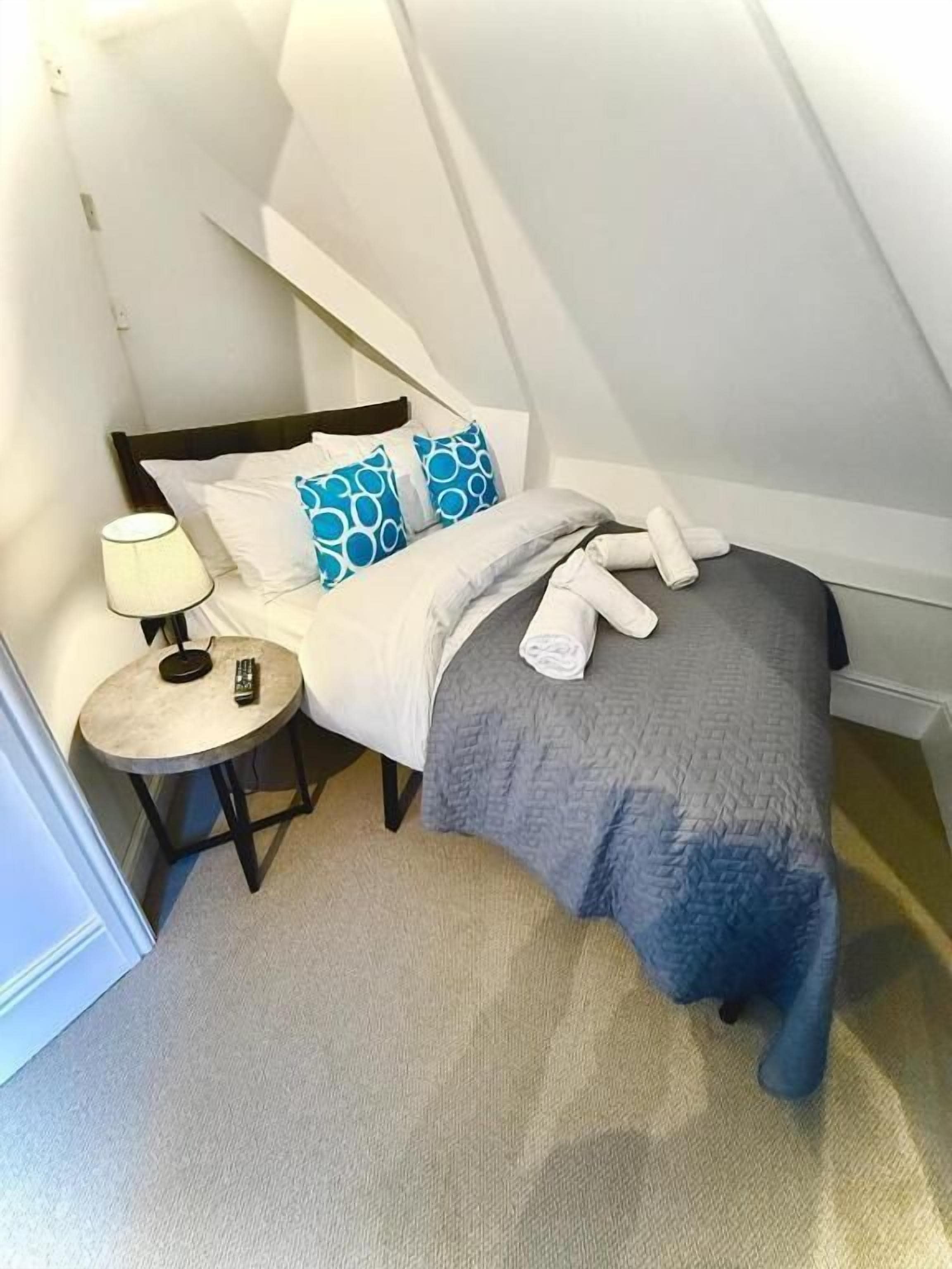 Un dormitorio con cama, mesita de noche y lámpara.
