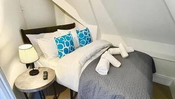 Un dormitorio con cama, mesita de noche y lámpara.