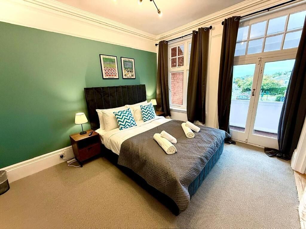 A hotel room with a bed, a nightstand, a window with curtains, and a view of the outside.